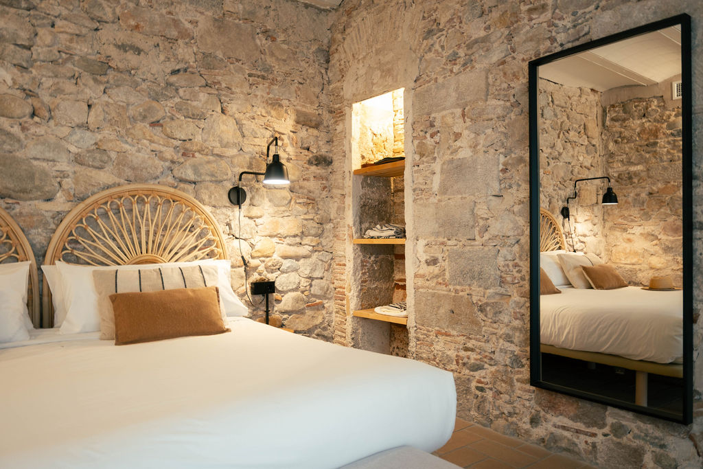 Morning side-light across a stone wall in a Bon Dia Residences apartment in Girona Old Town